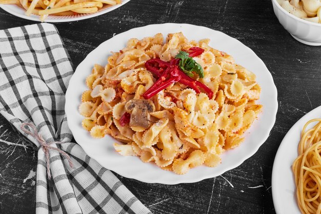 Pasta in tomato sauce in a white plate on black background. 