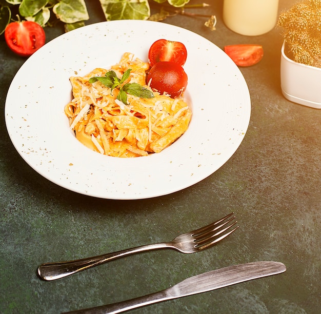 Free photo pasta in tomato sauce with chopped parmesan , tomato and basilic.