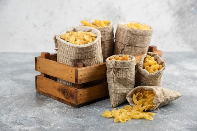 Pasta varieties in rustic basket inside a wooden tray.