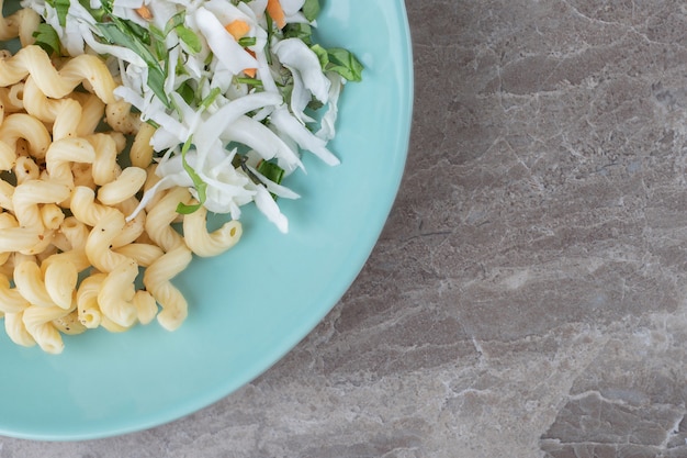 Free photo pasta with fresh salad and egg on blue plate.