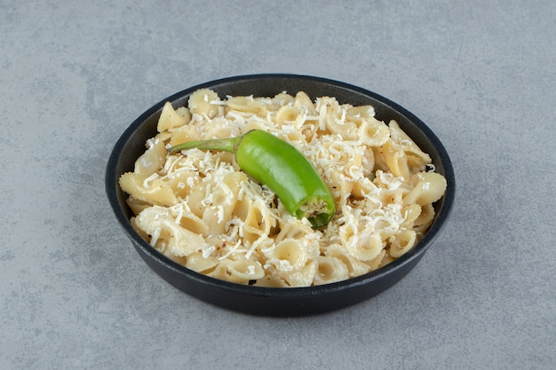 pasta with grated cheese on black plate.