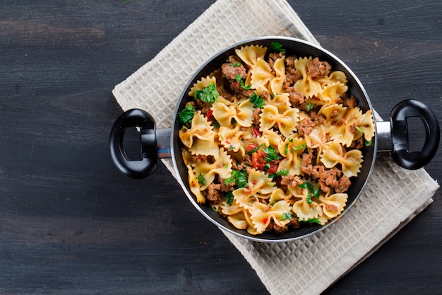 Free photo pasta with meat in a pan on wooden table