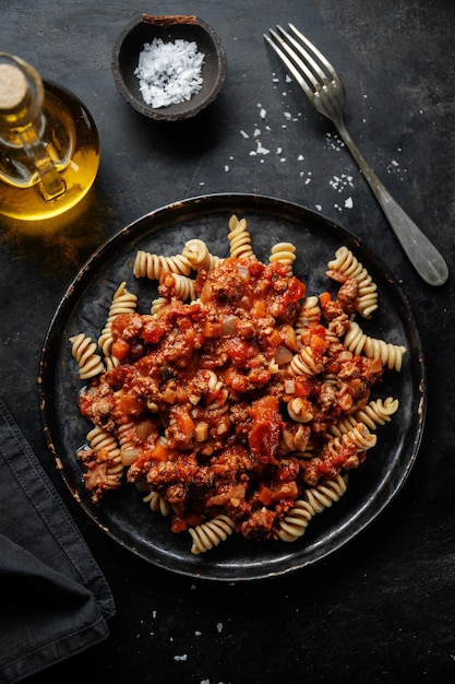 Free photo pasta with sauce bolognese served on plate on dark background