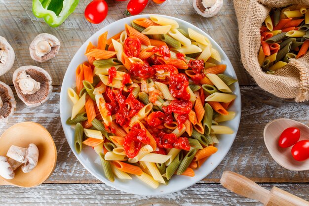 Pasta with sauce, tomato, mushroom, rolling pin, pepper in a plate