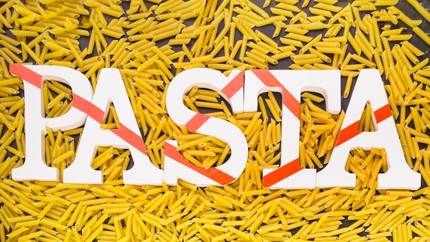 Free photo pasta word surrounded by uncooked penne