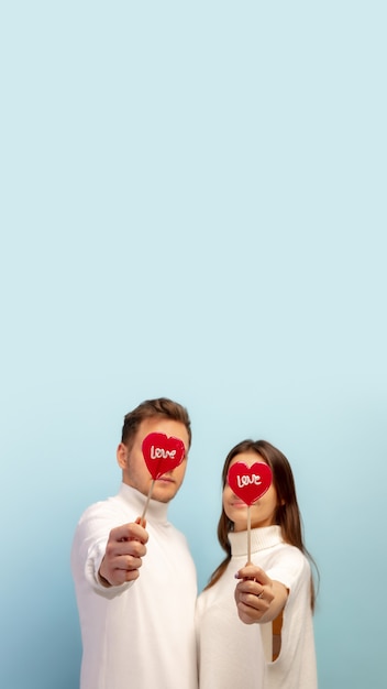 Pastel. Beautiful couple in love on blue studio background. Saint Valentine's Day, love, relationship and human emotions concept. Copyspace. Young man and woman look happy together.