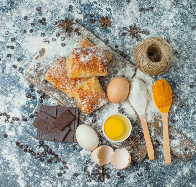 Free photo pastries with flour, chocolate, spices, eggs, thread top view on concrete and cutting board