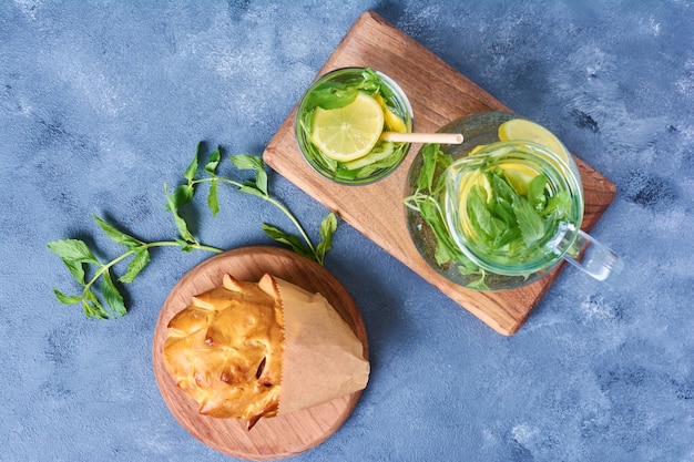 Free photo pastry bun with mochito on a wooden board on blue