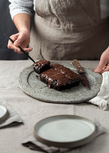 Pastry chef cutting and putting chocolate cake on plate