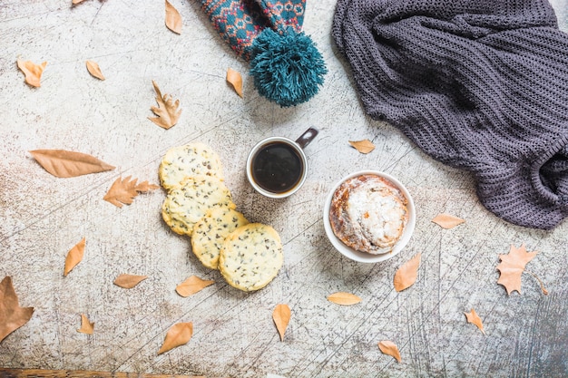 Free photo pastry and coffee near leaves and warm clothes