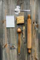 Free photo pastry; rolling pin; spoon; egg; flour and notepad on wooden surface