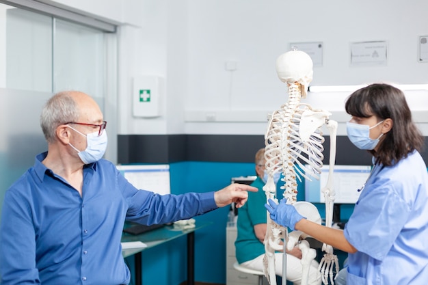 Free photo patient and nurse with face masks looking at spine bones