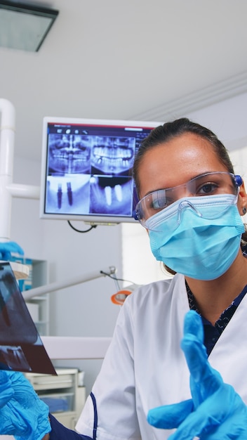 Patient pov looking at dentist asking for dental x-ray showing teeth image. Stomatology specialist wearing protective mask, working in modern stomatological clinic, explaining radiography of tooth