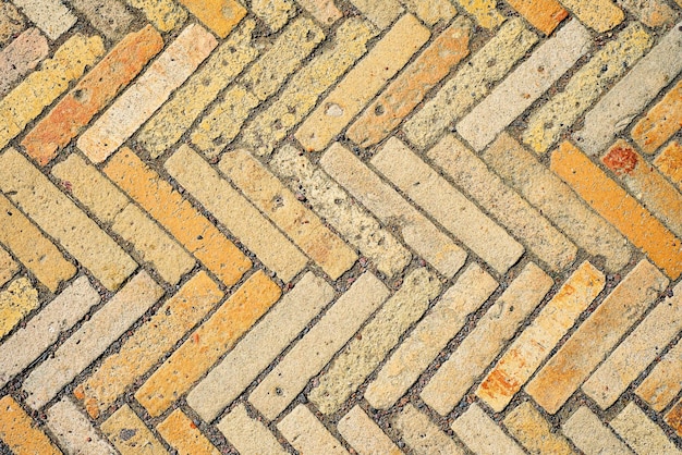 Free photo pattern with rectangular yellow brick tiles in the form of a herringbone diagonal texture abstract background of old brick ceramic cobblestone top view idea for easy desk wallpaper