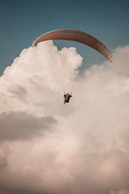 Peaceful scenery of paragliding in the cloudy sky - vertical shot