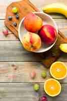 Free photo peach; apples; grapes; blueberries; banana and halved oranges on wooden desk