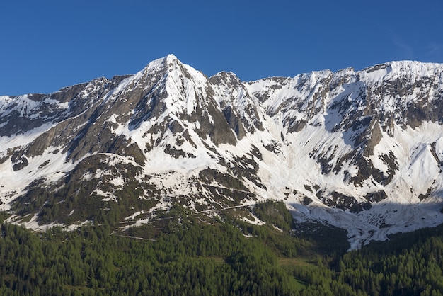 Peak of the mountains covered in snow against the blue sky in Ticino, Switzerland