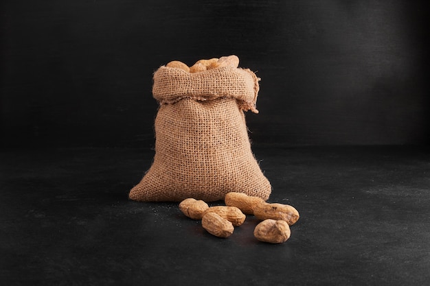 Peanut shells out of a rustic parcel on black background. 