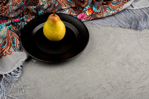 Free photo pear ripe mellow juicy inside black plate on a grey and colorful floor