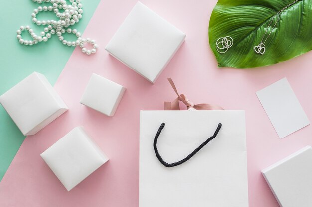 Pearls necklace and many white boxes with shopping bag on pink backdrop