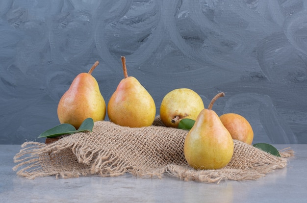 Free photo pears on a board covered with a piece of cloth on marble background.