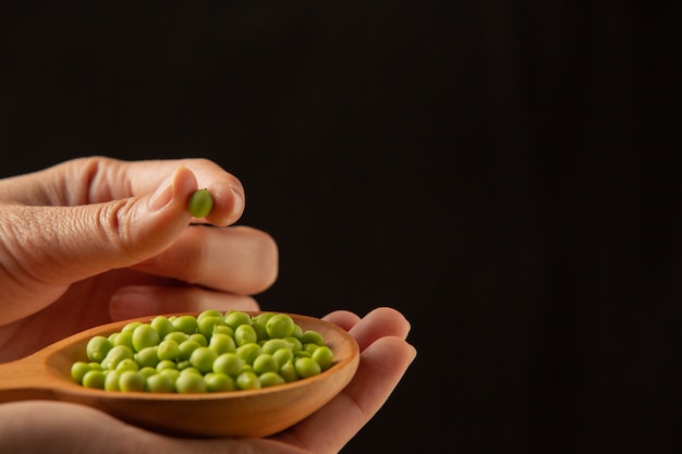 Free photo peas place a wooden spoon on your hand.