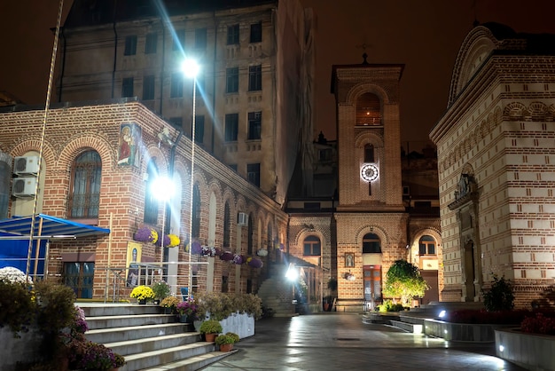 Pedestrian street at night with illumination, church, buildings, greenery and flowers in Bucharest, Romania