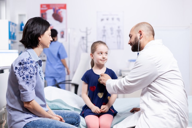 Free photo pediatrician checking health of child using stethoscope in hospital office during consultation. healthcare physician specialist in medicine providing health care services treatment examination.