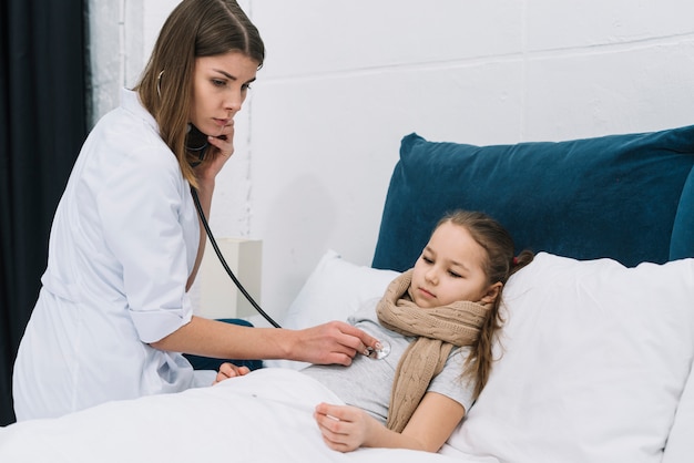 Free photo pediatrician woman examining little sick girl with stethoscope