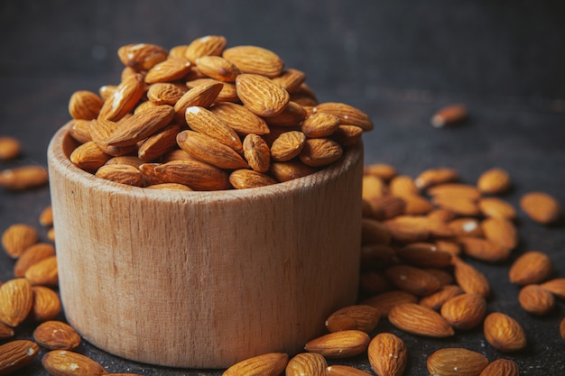 Free photo peeled almonds in a wooden bowl on a dark table