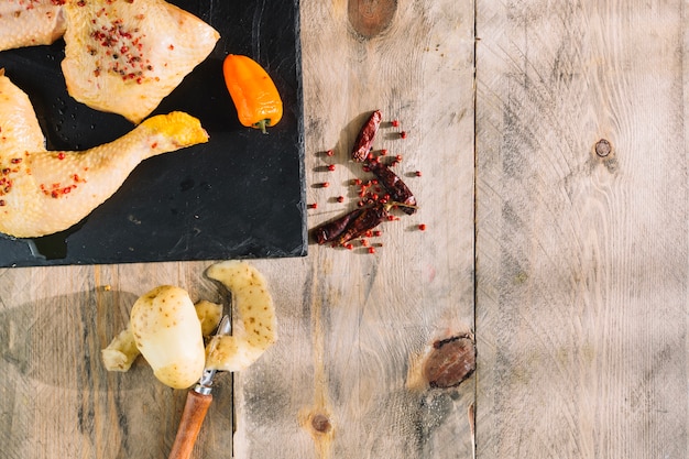 Peeled potato near raw chicken legs