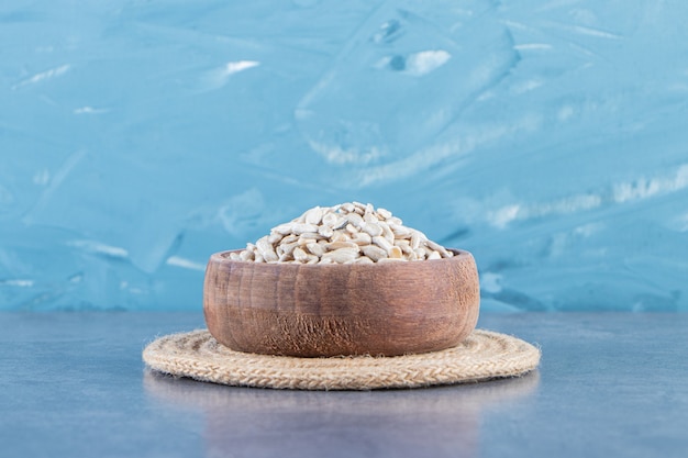 Peeled sunflower seeds in a bowl on the trivet on the marble surface