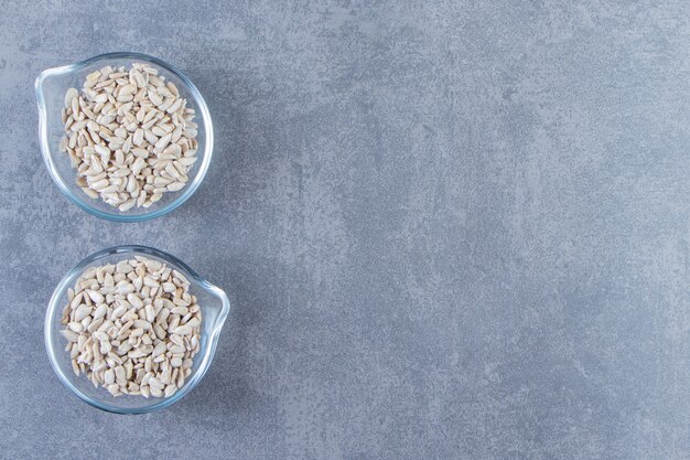 Peeled sunflower seeds in a glass bowls, on the marble background.