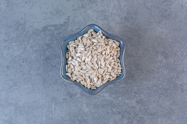 Peeled, tasty sunflower seeds in bowl, on the marble surface