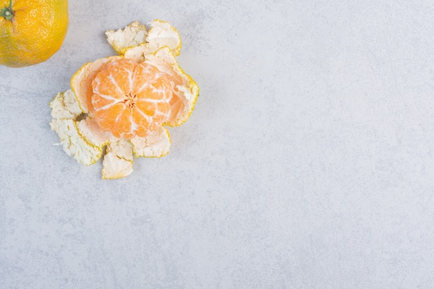 Peeled and whole tangerine on grey background. 