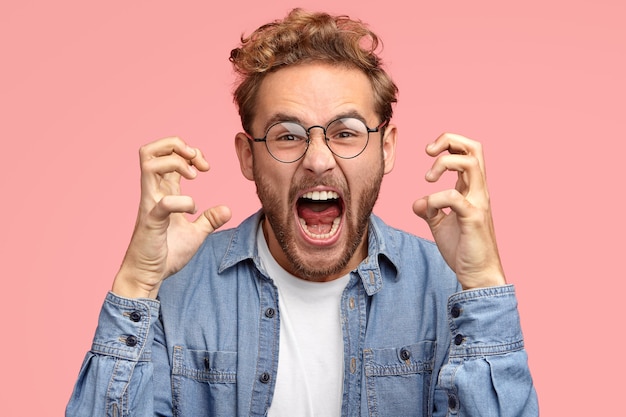 Peevish annoyed man gestures angrily, expresses negative emotions, keeps mouth widely opened