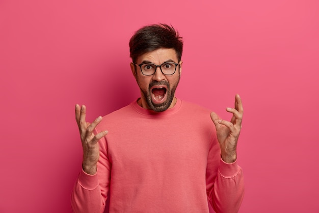 Free photo peevish outraged man gestures angrily and screams loudly