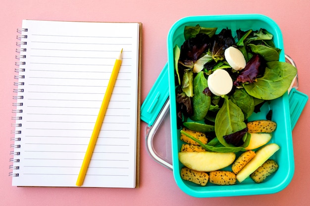 Pencil and notebook near salad