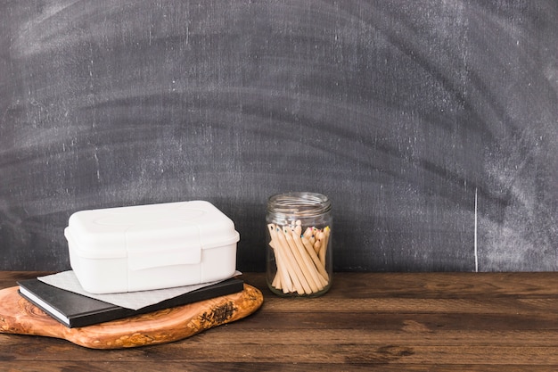 Pencils near plastic lunchbox and notebook