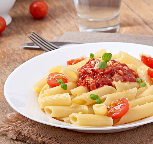 Free photo penne pasta with bolognese sauce, parmesan cheese and basil