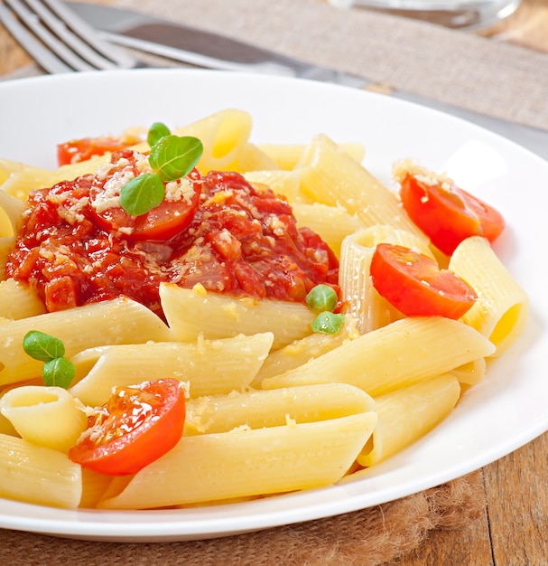 Free photo penne pasta with bolognese sauce, parmesan cheese and basil