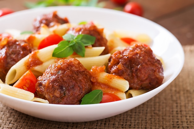 Free Photo penne pasta with meatballs in tomato sauce in a white bowl