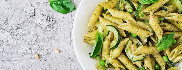 Free Photo penne pasta with  pesto sauce, zucchini, green peas and basil. italian food. top view. flat lay.