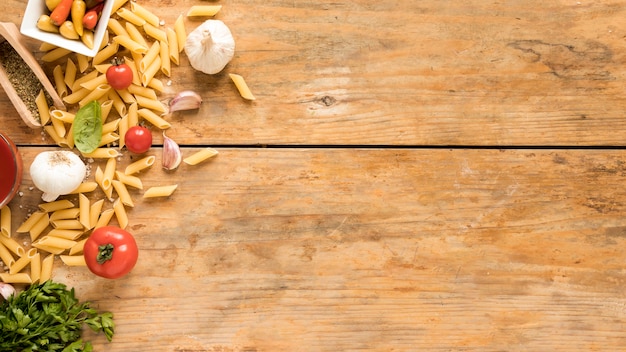 Free Photo penne pasta with vegetables ingredients on old wooden table