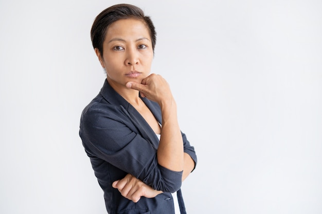 Free photo pensive asian business woman touching chin with fingers