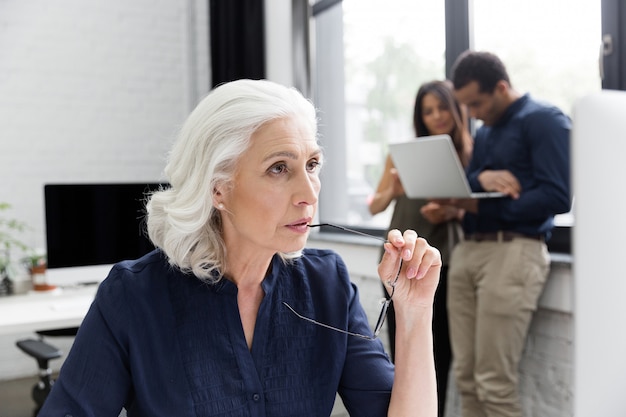 Free Photo pensive ature business woman working at her workplace