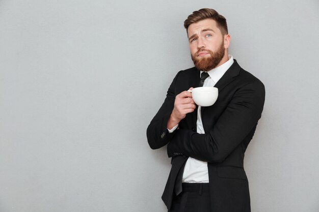 Pensive bearded man in holding cup of coffee