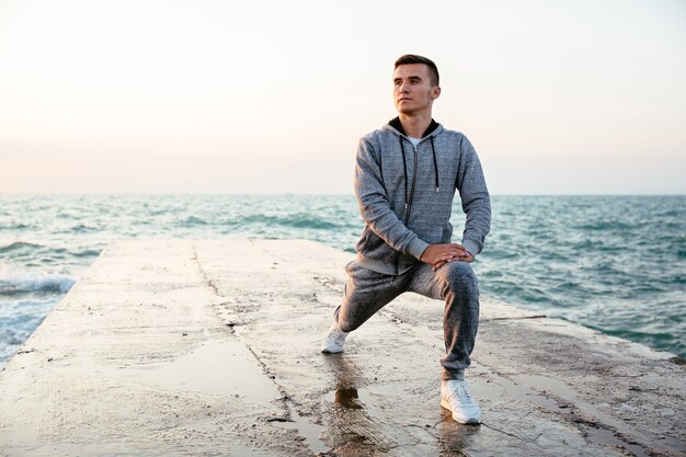 Pensive concentrated man in sportswear doing lunges, stretching