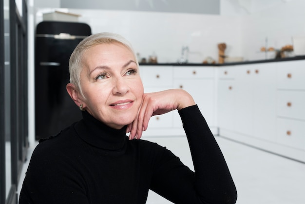 Pensive elder woman posing in the kitchen