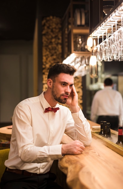 Pensive guy sitting at bar counter